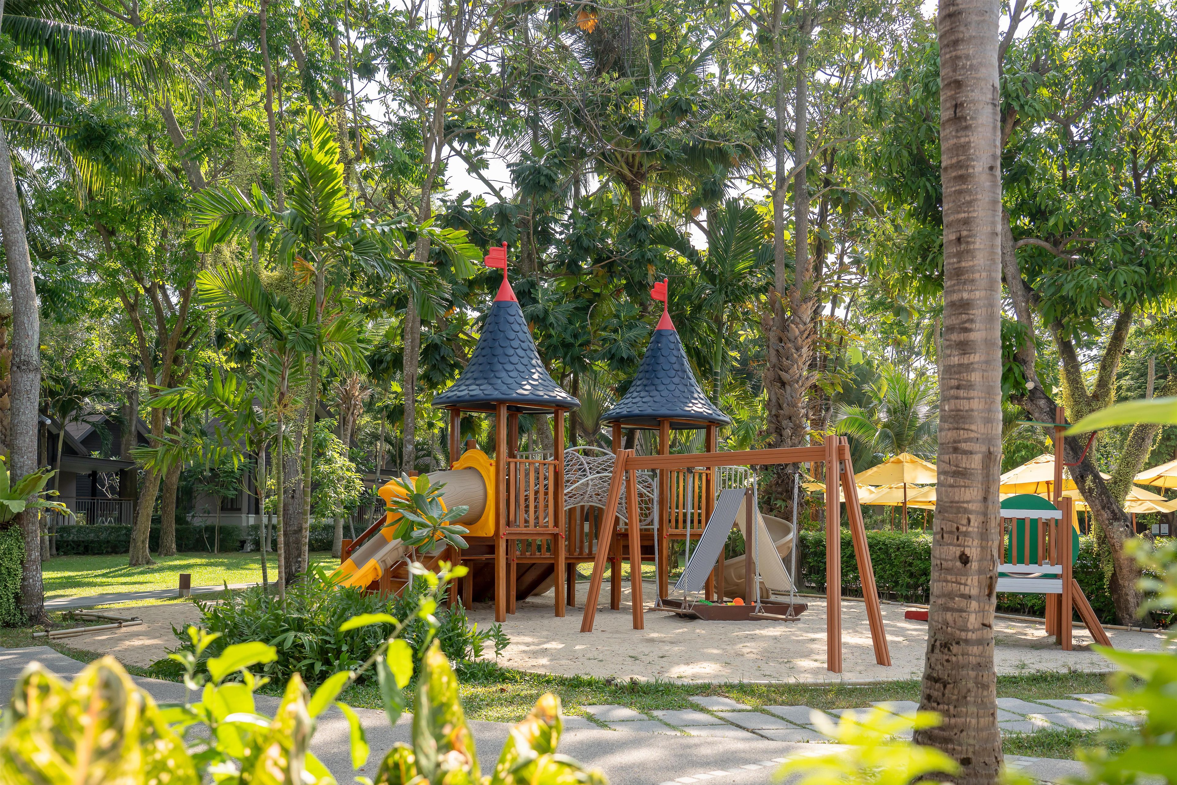 A playground with two play structures, a slide, and a swing set.