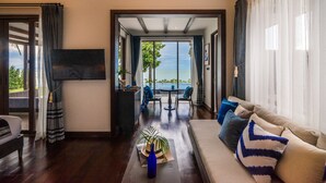 A modern living room with a sofa, TV, and a view of the sea. - NH Collection Samui Peace Resort (Koh Samui)