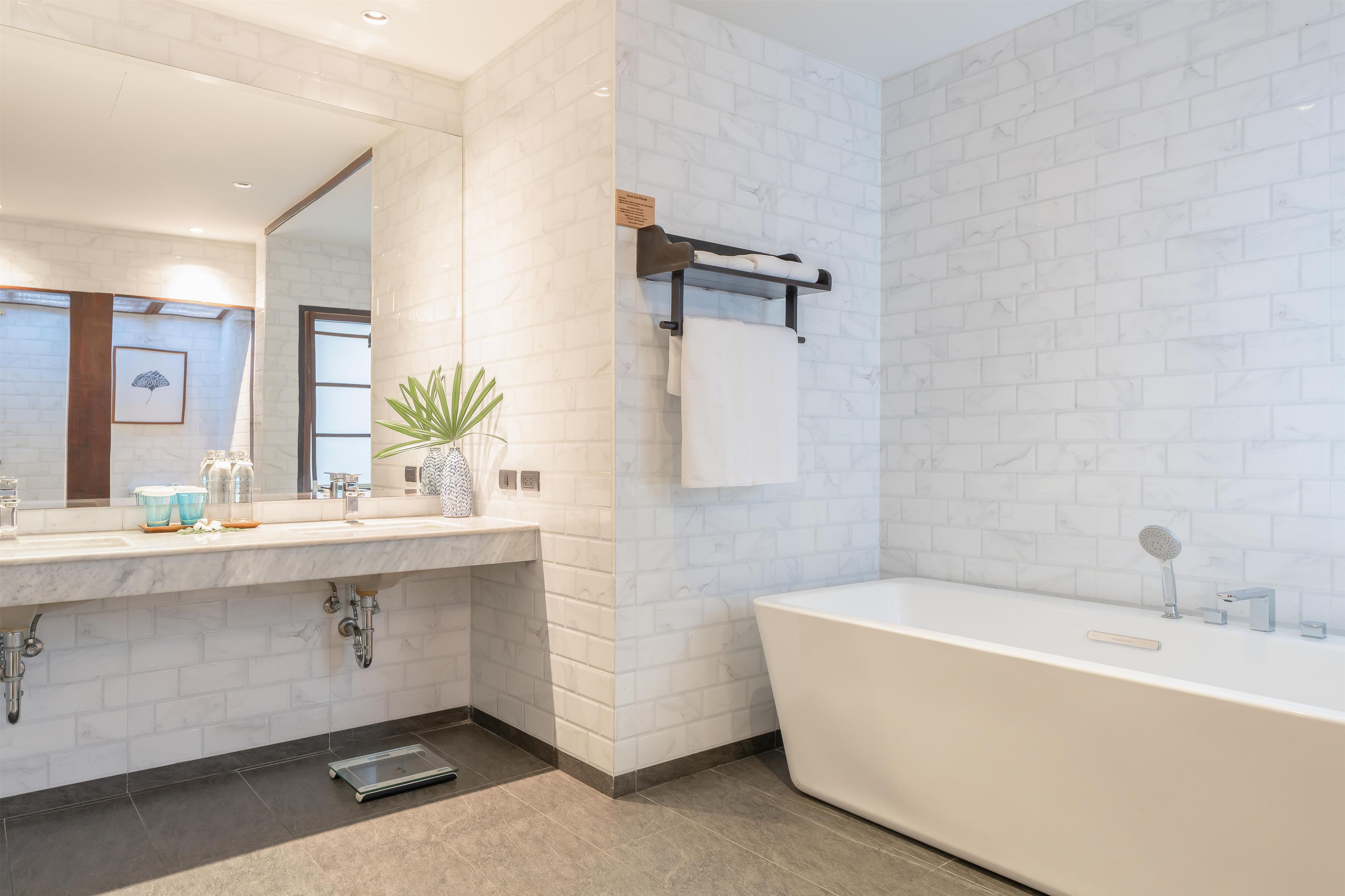 Un baño moderno con un lavabo de mármol blanco, una bañera independiente y un perchero para toallas.
