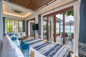 Un dormitorio con una cama grande, televisión y vista al mar a través de un ventanal corredero.