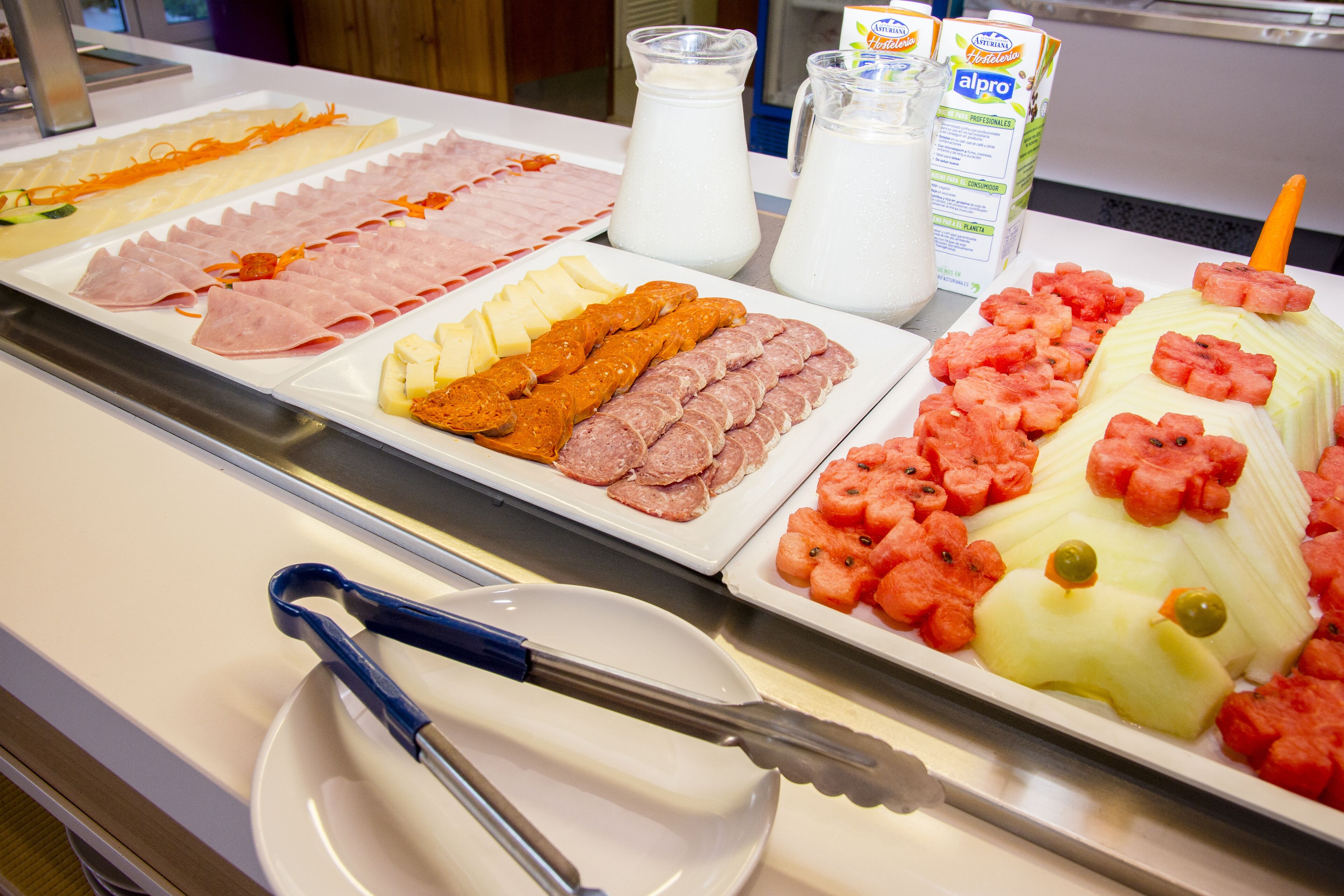 Een buffet met diverse gerechten, zoals vleeswaren, kazen en fruit.