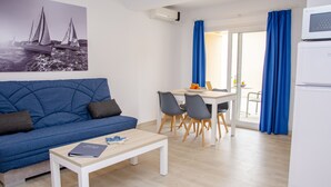 Ein modernes Wohnzimmer mit einem blauen Sofa, einem weißen Couchtisch und einem Essbereich mit Tisch und Stühlen.