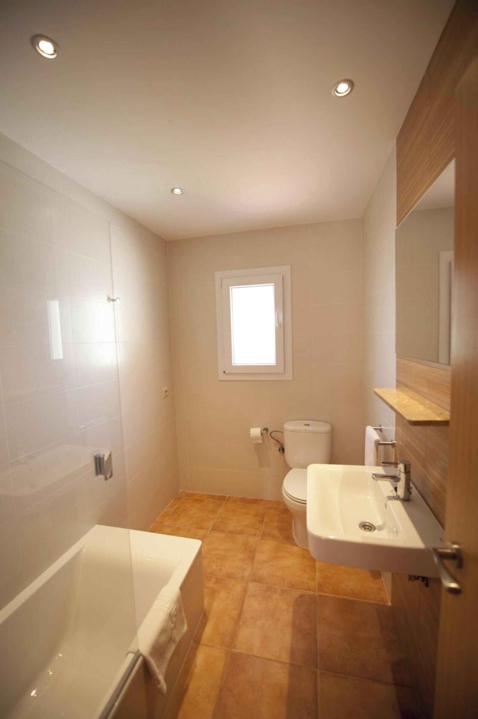Un baño con bañera, inodoro, lavabo y ventana.