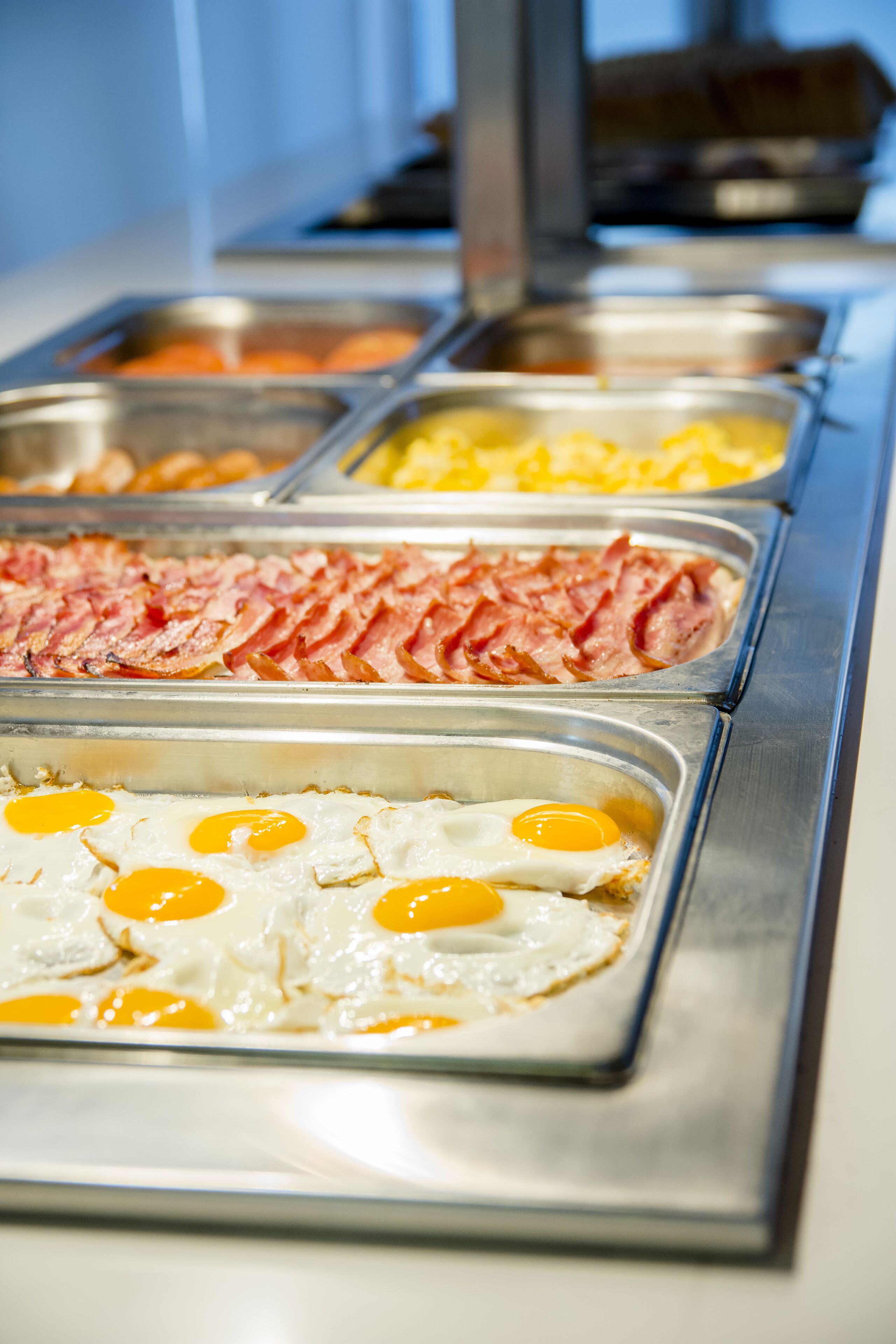 A buffet with various food options including eggs, bacon, and other breakfast items.