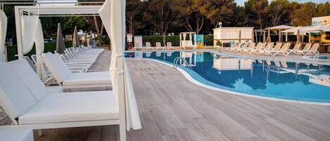 Un espace aménagé au bord de la piscine, avec des chaises longues et un coin salon abrité.