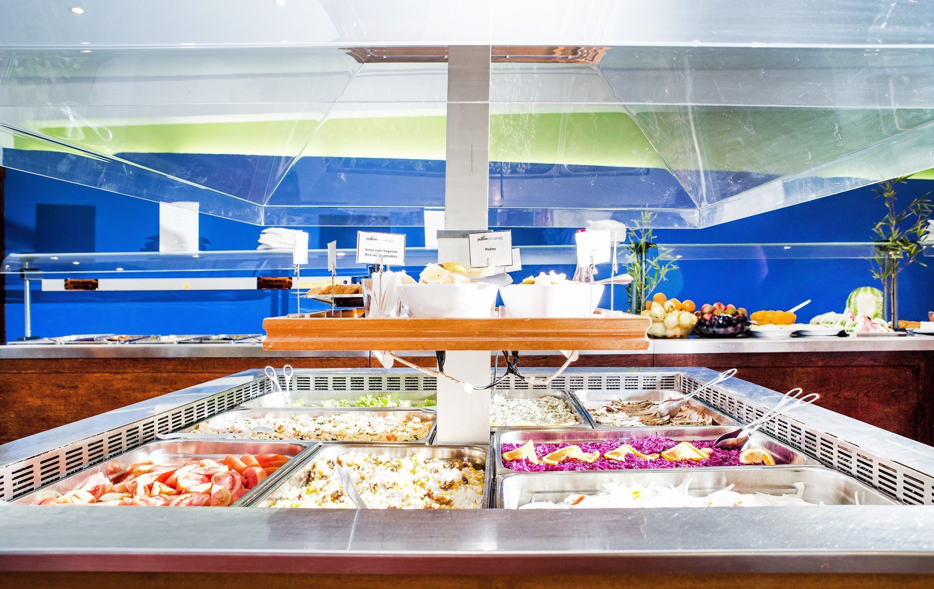 A buffet with various food options, including rice, vegetables, and fruits.