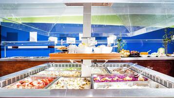 A buffet with various food options, including rice, vegetables, and fruits.