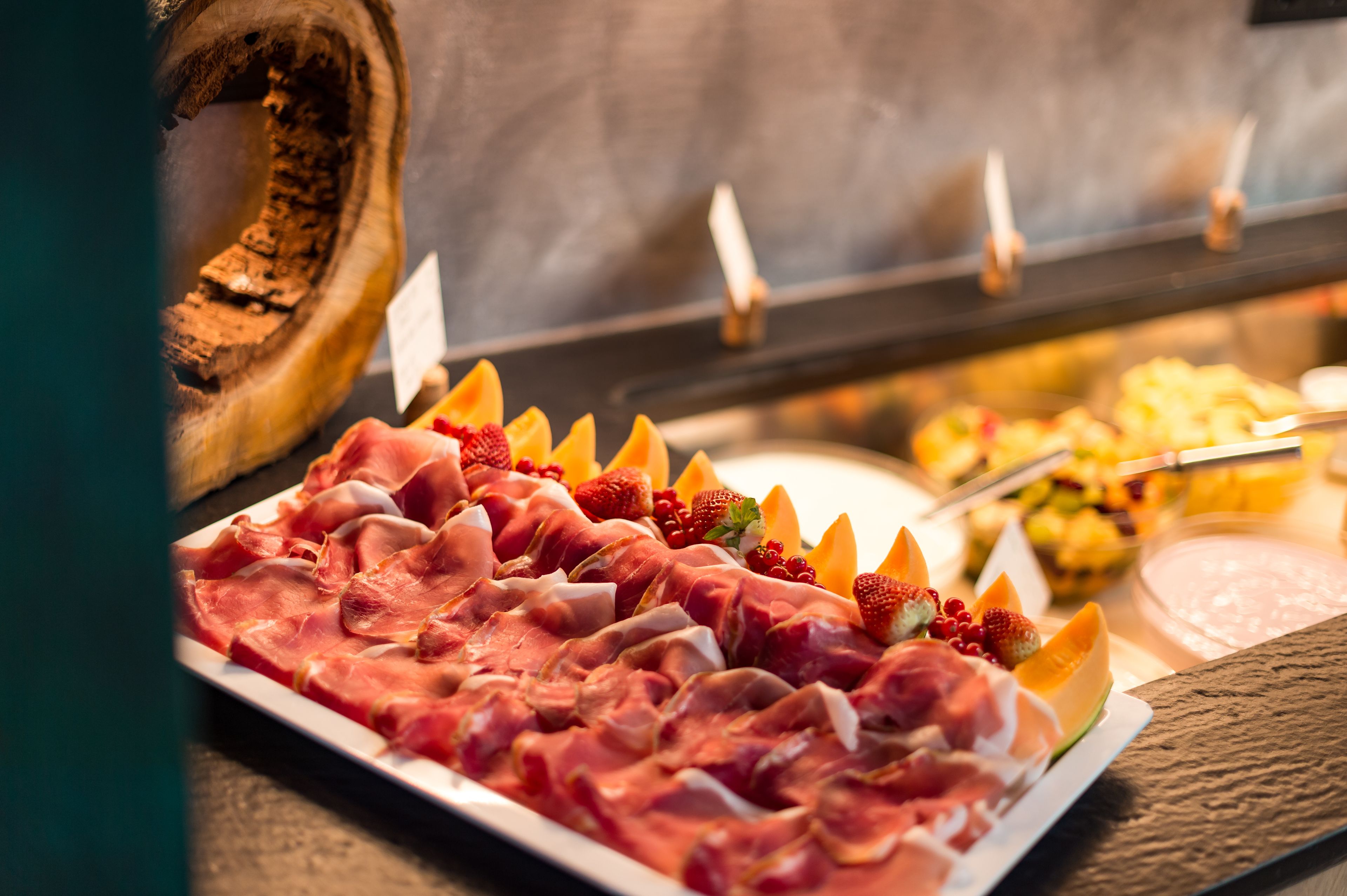 Een buffet met verschillende vleessoorten en fruit.
