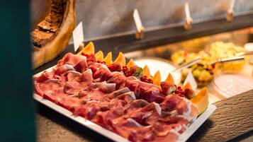 Een buffet met verschillende vleessoorten en fruit.