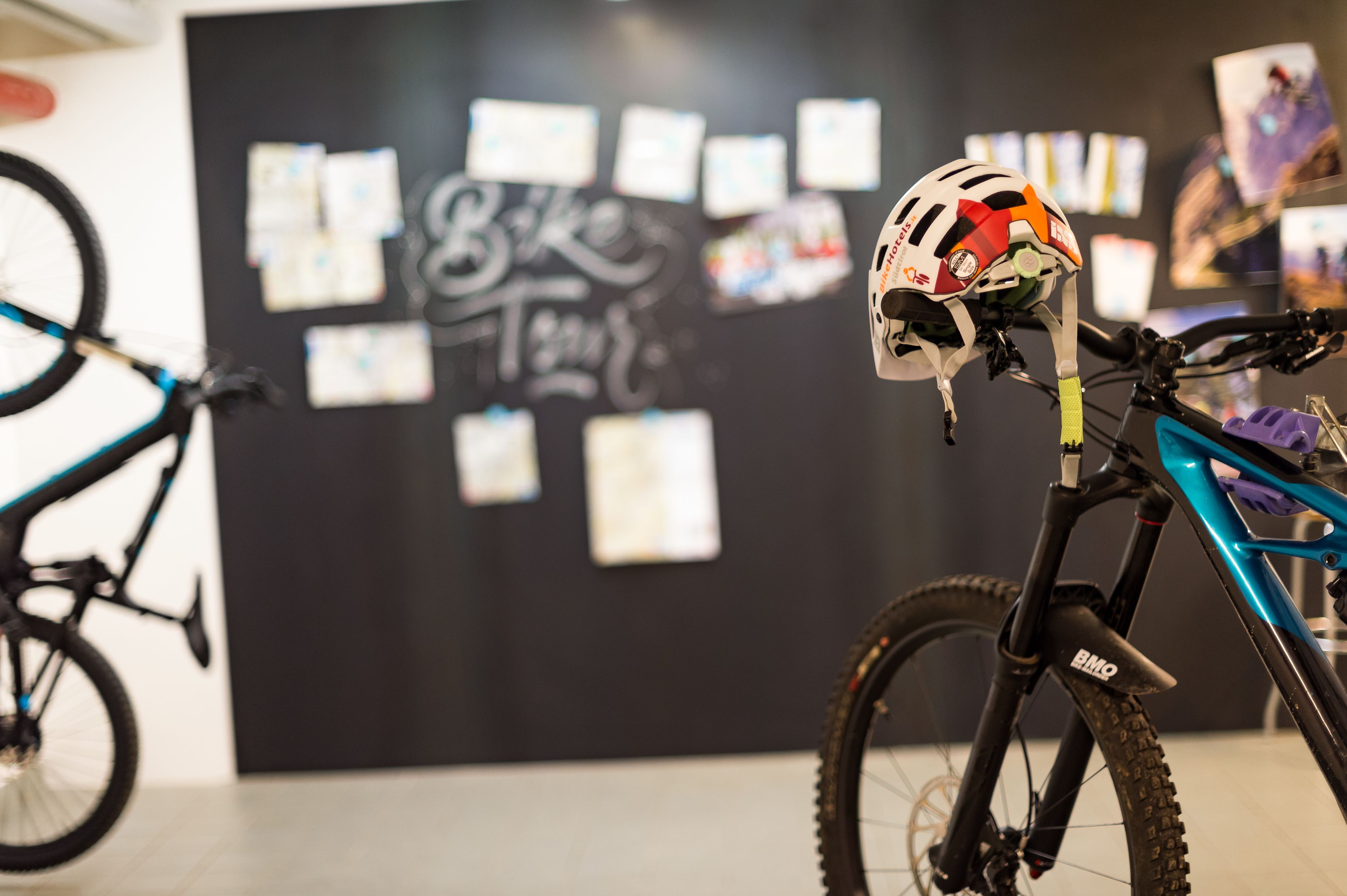 Ein Fahrrad mit Helm auf dem Sattel, eine Wand mit Notizen und ein Plakat in einem Zimmer.