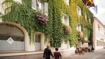 Un edificio con pareti coperte d'edera e un cartello con su scritto "KRONE".