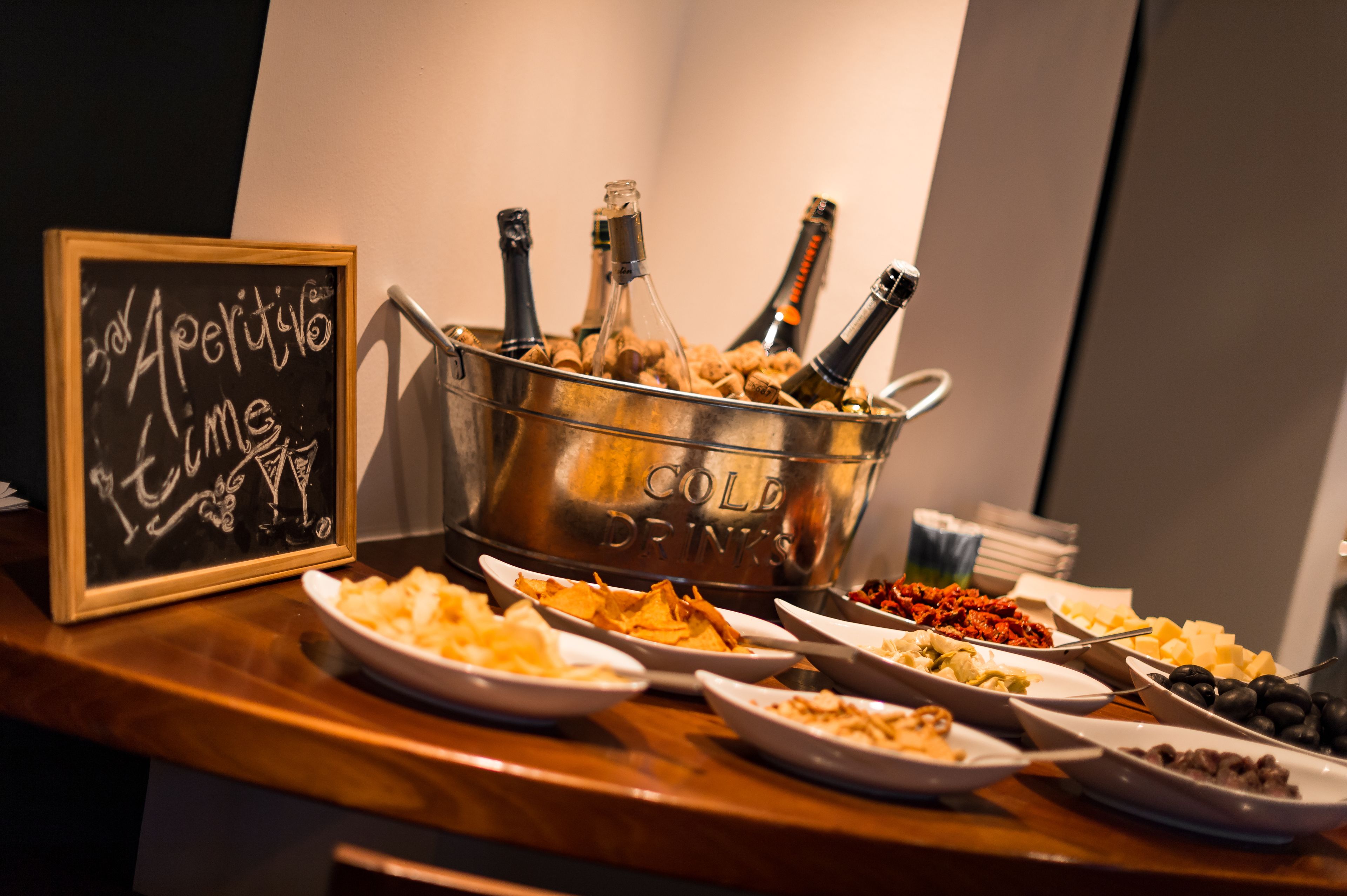 Una mesa de buffet con varios platos y un balde con bebidas frías, que contiene botellas.