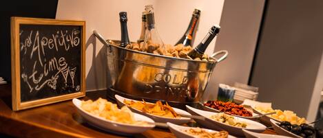 Una mesa de buffet con varios platos y un balde con bebidas frías, que contiene botellas.