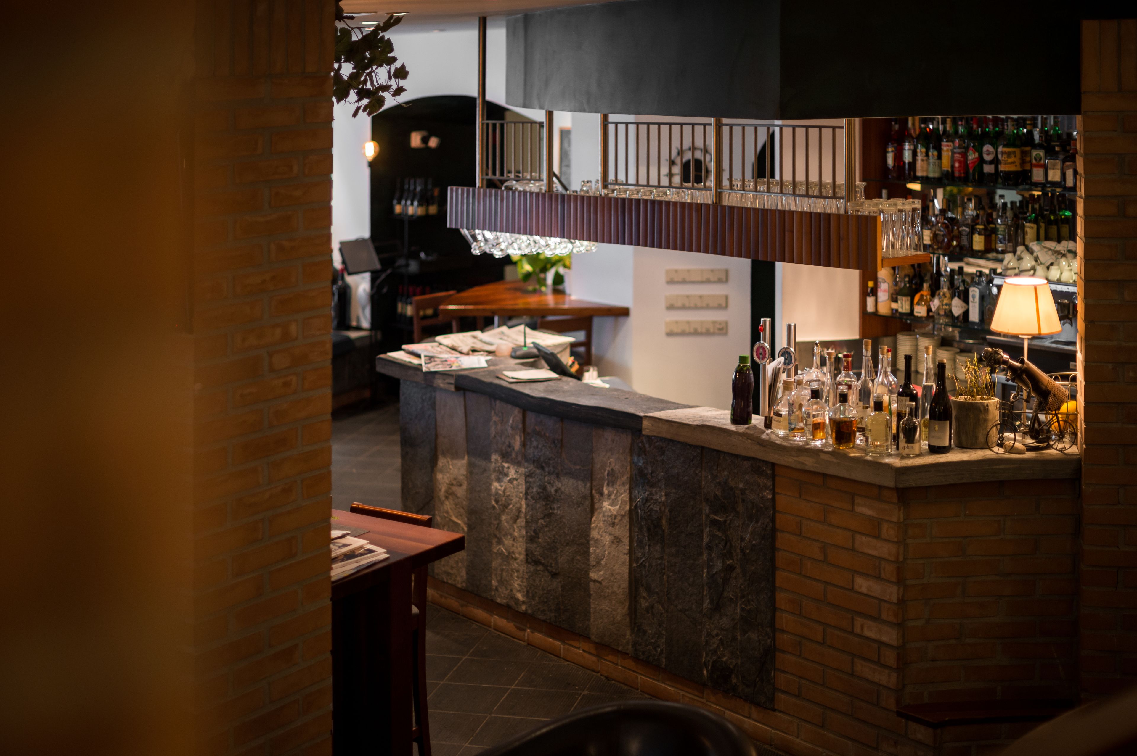 Una zona de bar con mostrador de piedra, estantes con botellas y una bicicleta.