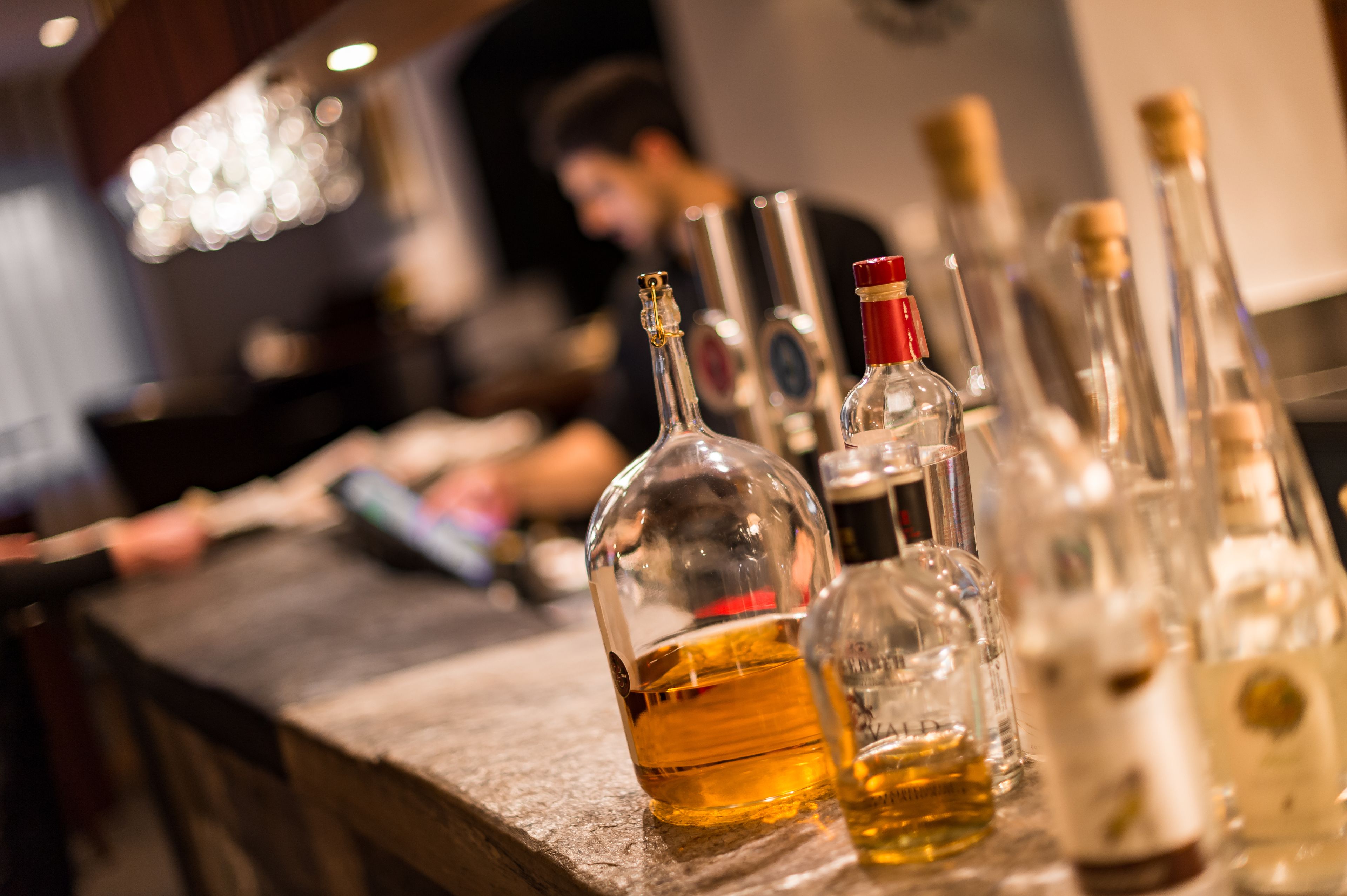 A bar counter with various bottles of alcohol, including a prominent bottle of whiskey.