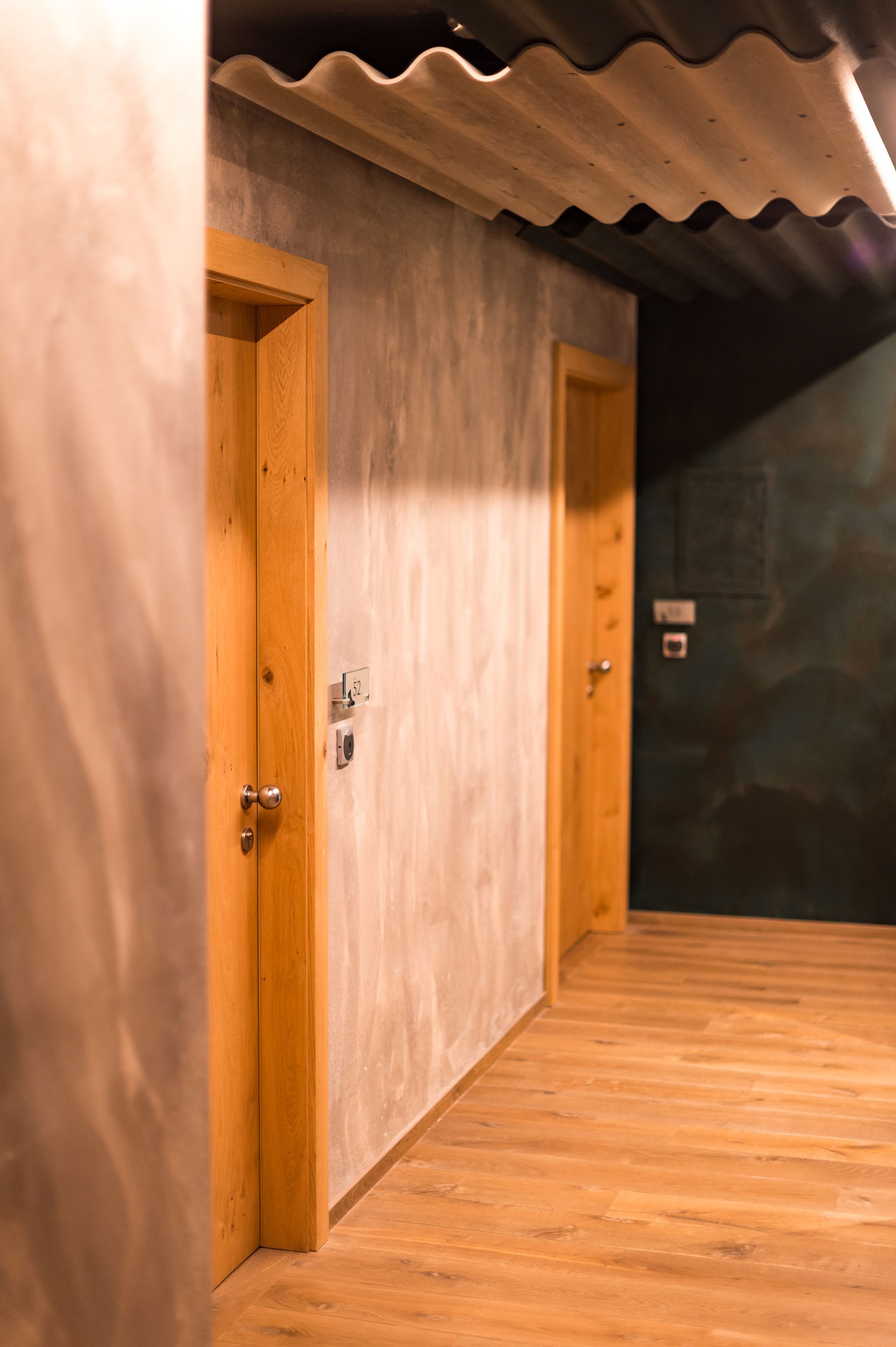 Un pasillo con puertas de madera y pared texturizada.