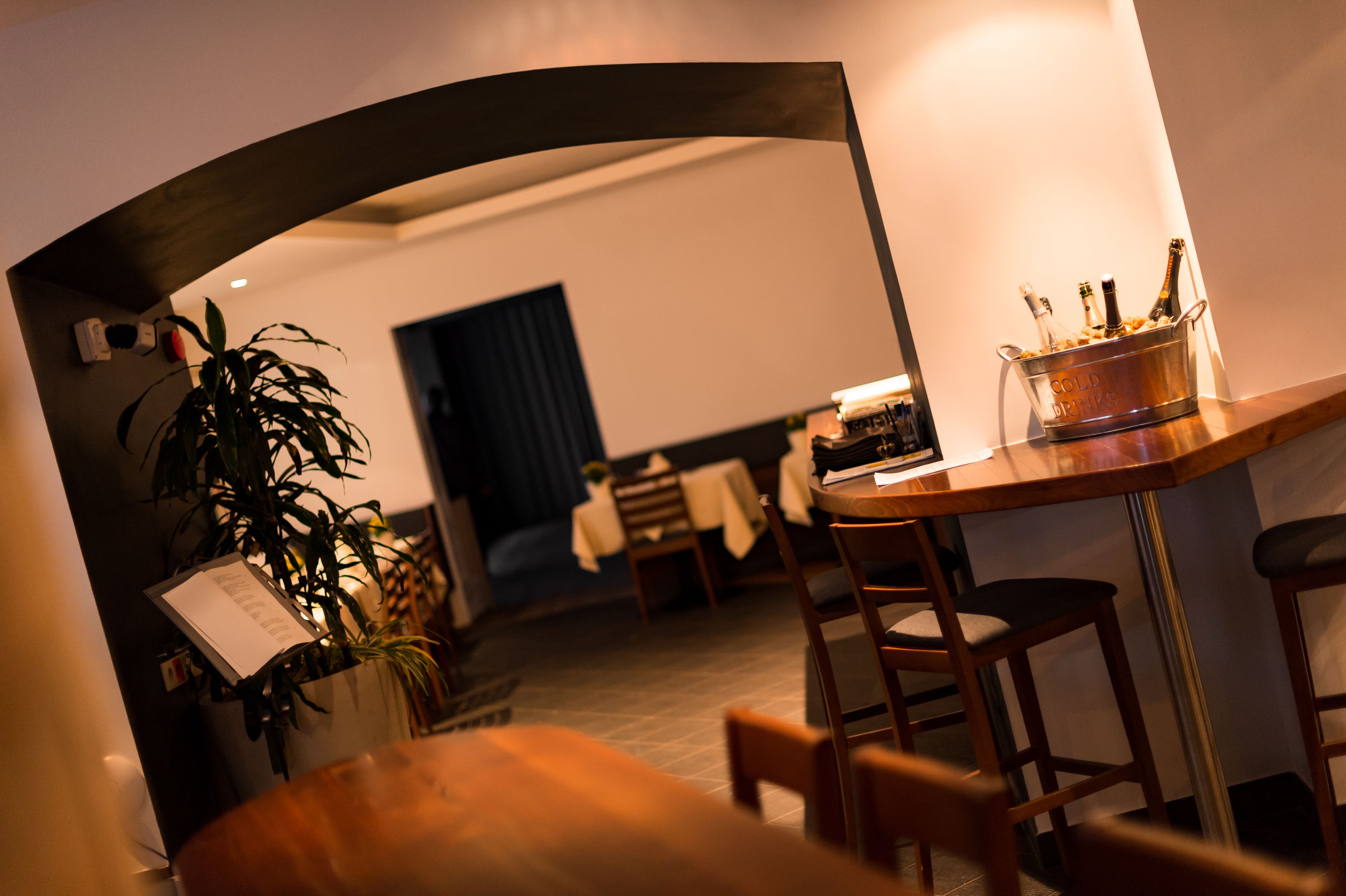 A bar area with a wooden bar counter, stools, and a bucket of champagne bottles.