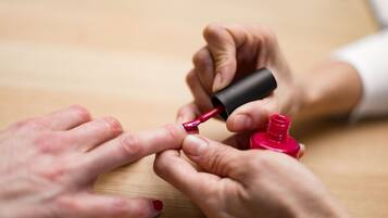 Nahaufnahme von Händen, die roten Nagellack auftragen.