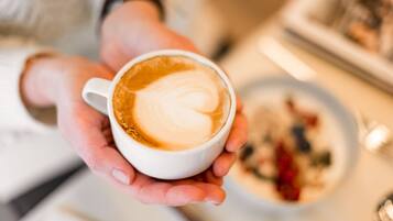A person holding a cup of coffee with a heart-shaped latte art.