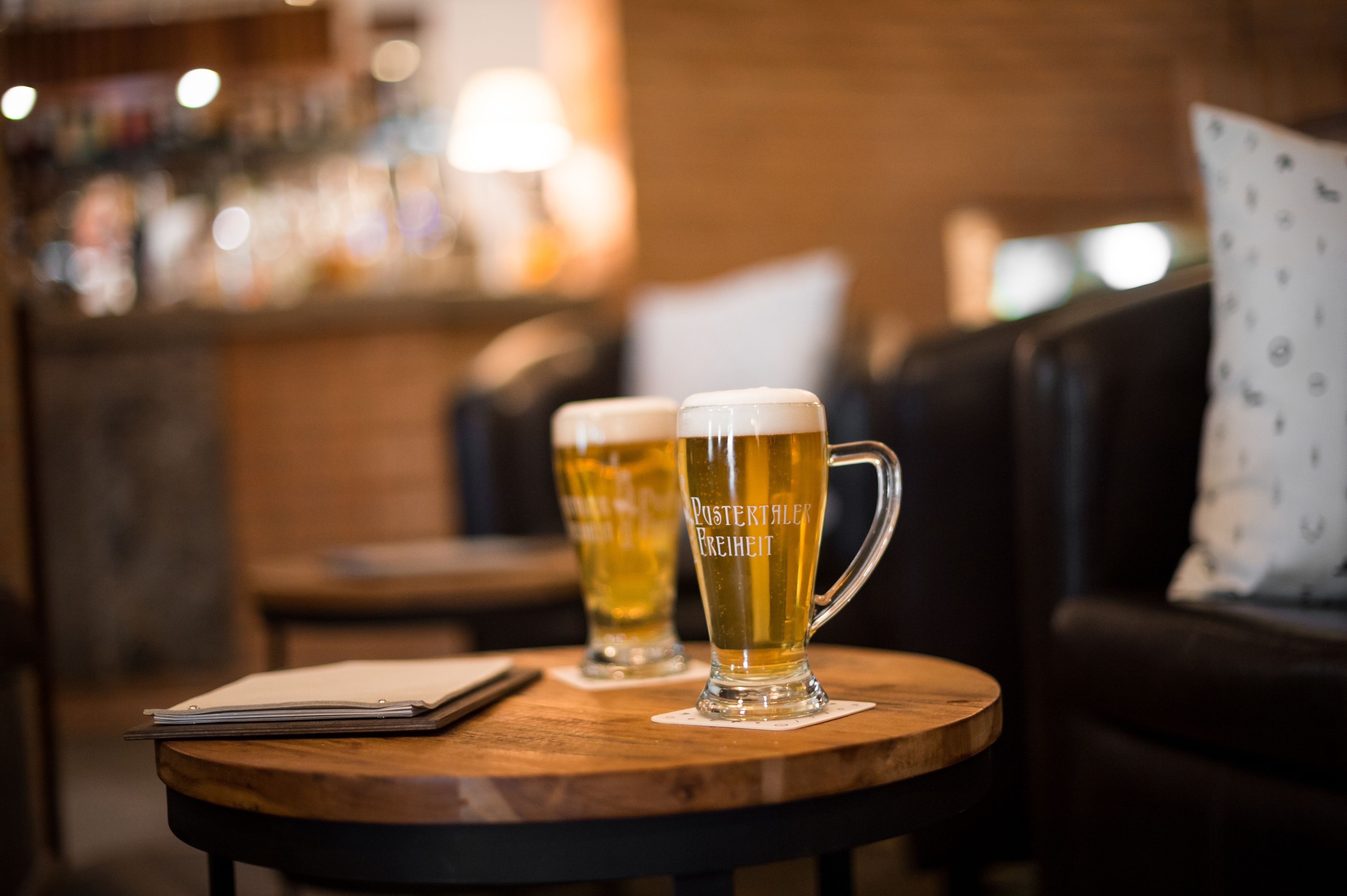 Two beer mugs on a wooden table with a notebook beside them.
