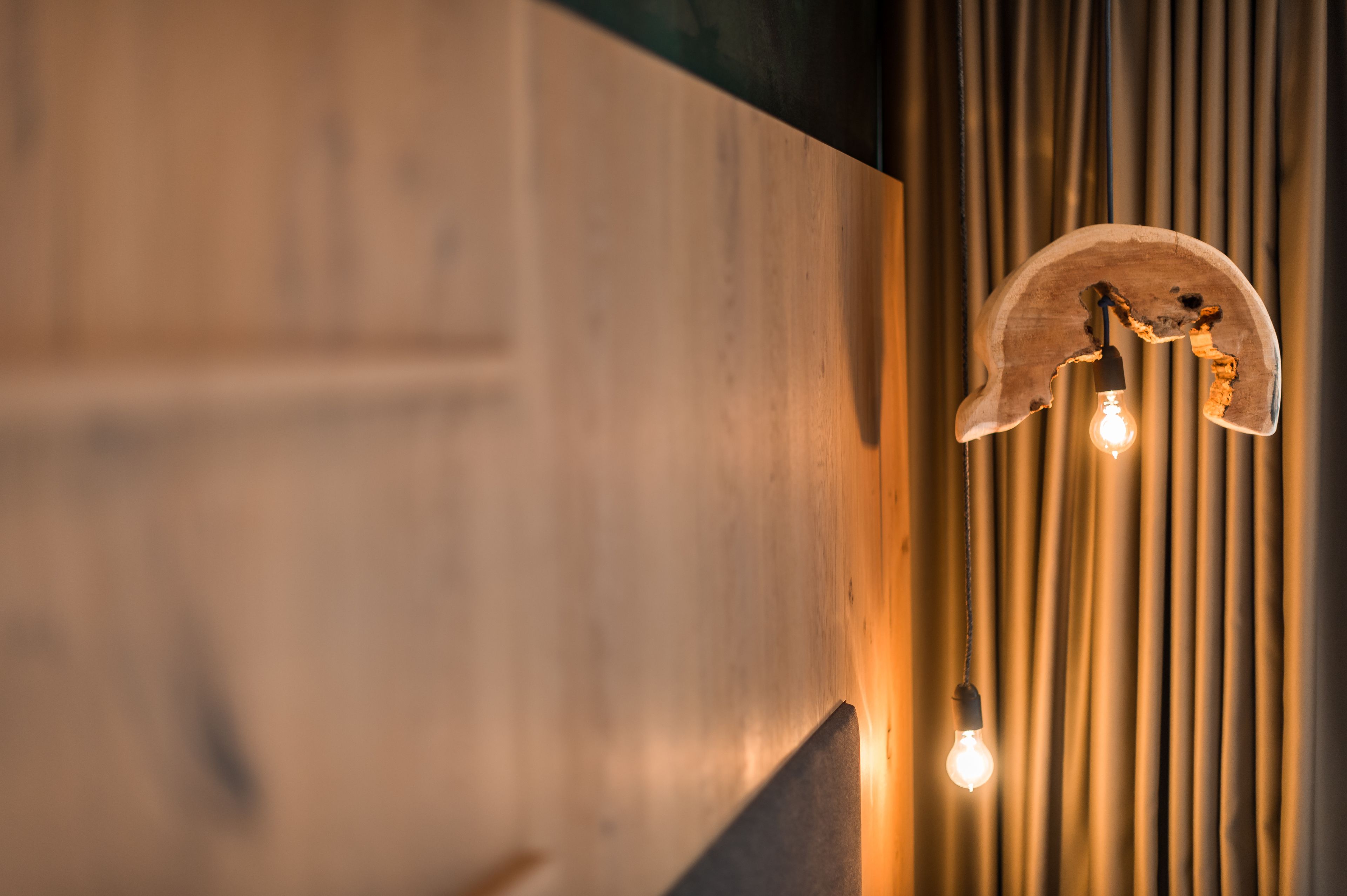 A wooden wall with a unique light fixture featuring two exposed bulbs.