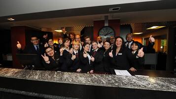 Un grupo de personas en la recepción de un hotel, con un reloj y un diseño moderno.
