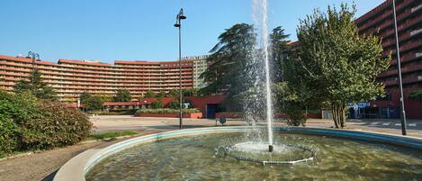 A fountain in a courtyard with a building in the background.