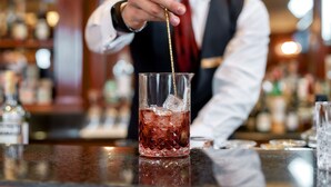 A bartender pouring a drink into a glass with ice cubes. - Ripamonti Residence & Hotel (Pieve Emanuele)