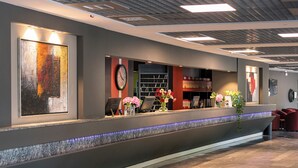 A reception area with a reception desk, a clock, and a wall-mounted artwork.