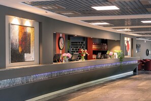 A reception area with a reception desk, a clock, and a wall-mounted artwork.