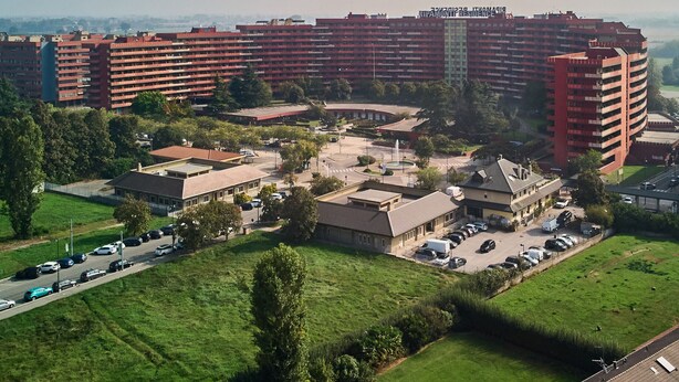 A high-rise residential building with multiple balconies, a central courtyard, and surrounding greenery.