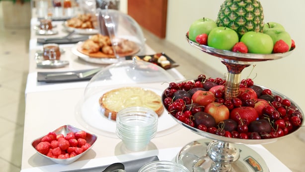 A buffet table with various food items including fruits, pastries, and a pie. - Ripamonti Residence & Hotel (Pieve Emanuele)