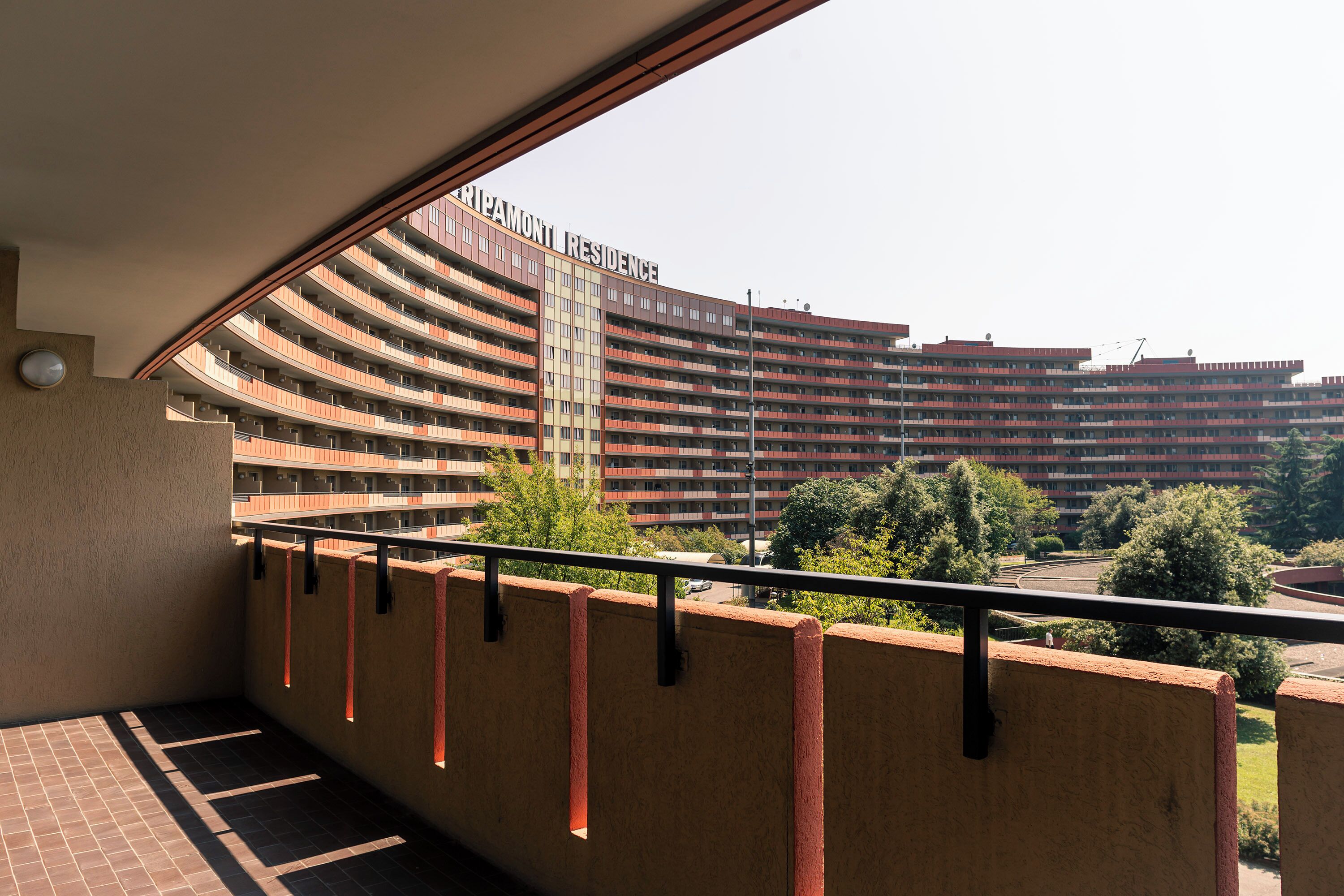 A view from a balcony overlooking a large, multi-story building with a curved facade and balconies.