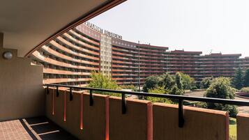 Vista desde un balcón que da a un edificio grande de varios pisos con fachada curva y balcones.