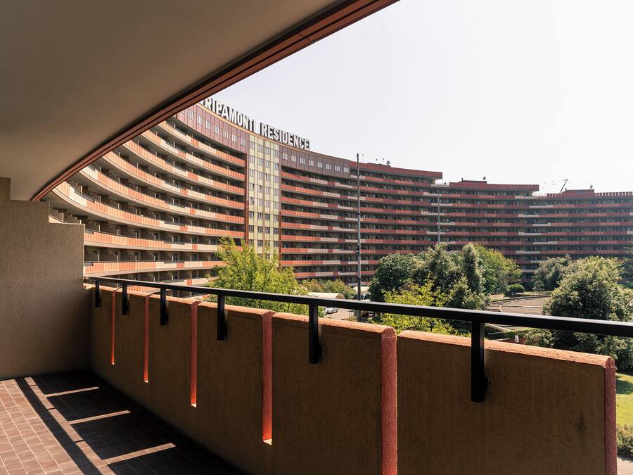 A view from a balcony overlooking a large, multi-story building with a curved facade and balconies.
