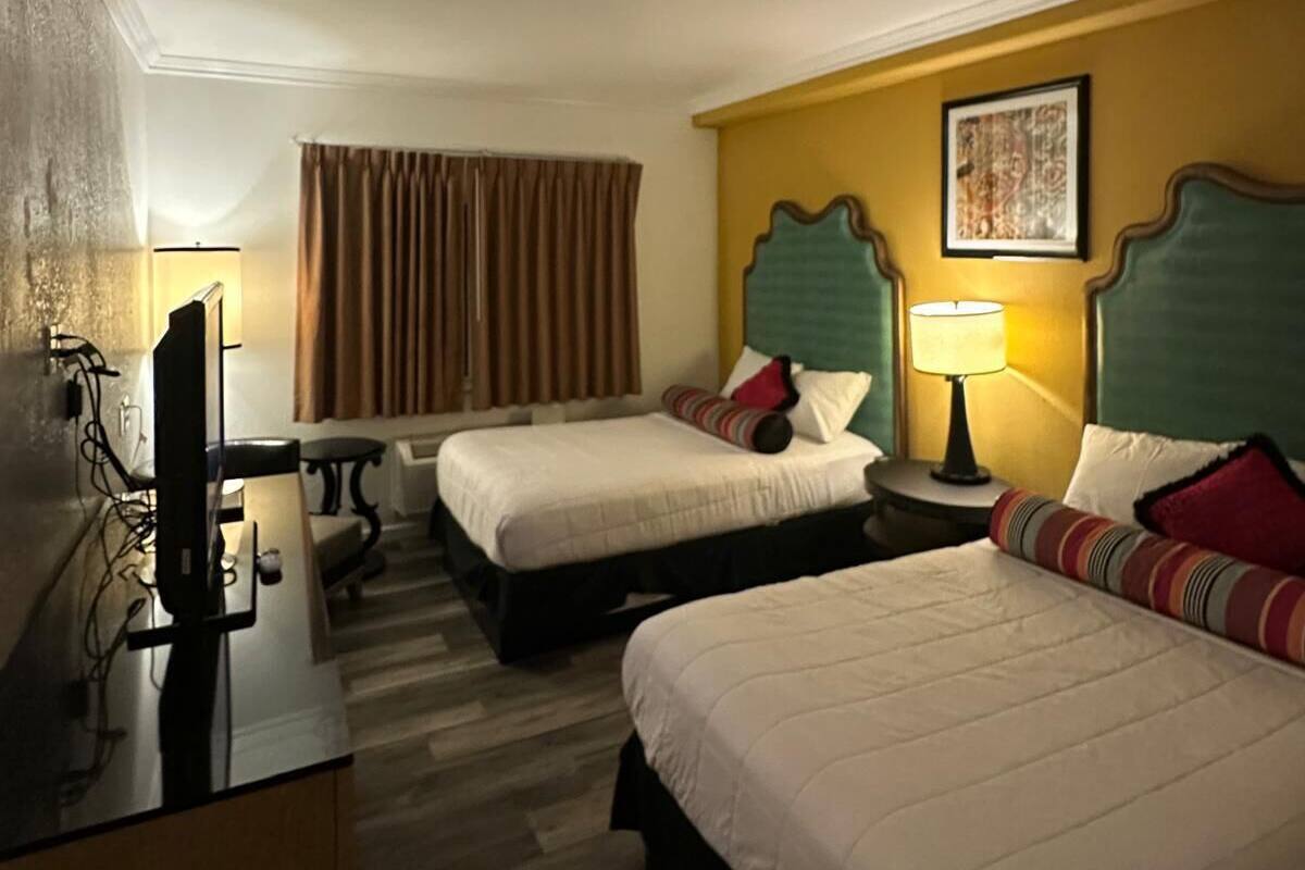 Ein Hotelzimmer mit zwei Betten, einem Schreibtisch, einem Stuhl und einem Fernseher.