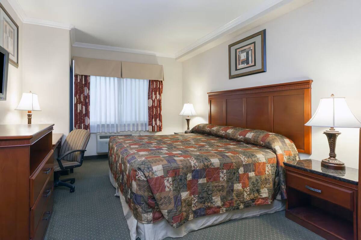 Ein Hotelzimmer mit Bett, Schreibtisch, Stuhl und zwei Nachttischlampen.