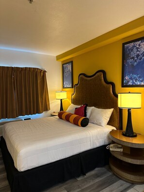 A hotel room with a large bed, two bedside tables with lamps, a headboard, and two framed pictures on the wall. - Howard Johnson by Wyndham Bakersfield (Bakersfield)