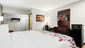 A hotel room with a bed, a desk, a television, and a microwave.
