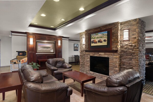 A living room with leather sofas, a stone fireplace, and a framed picture above it.