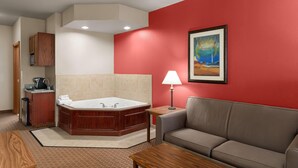 Une chambre d’hôtel avec une grande baignoire, un canapé, une machine à café et un tableau au mur.