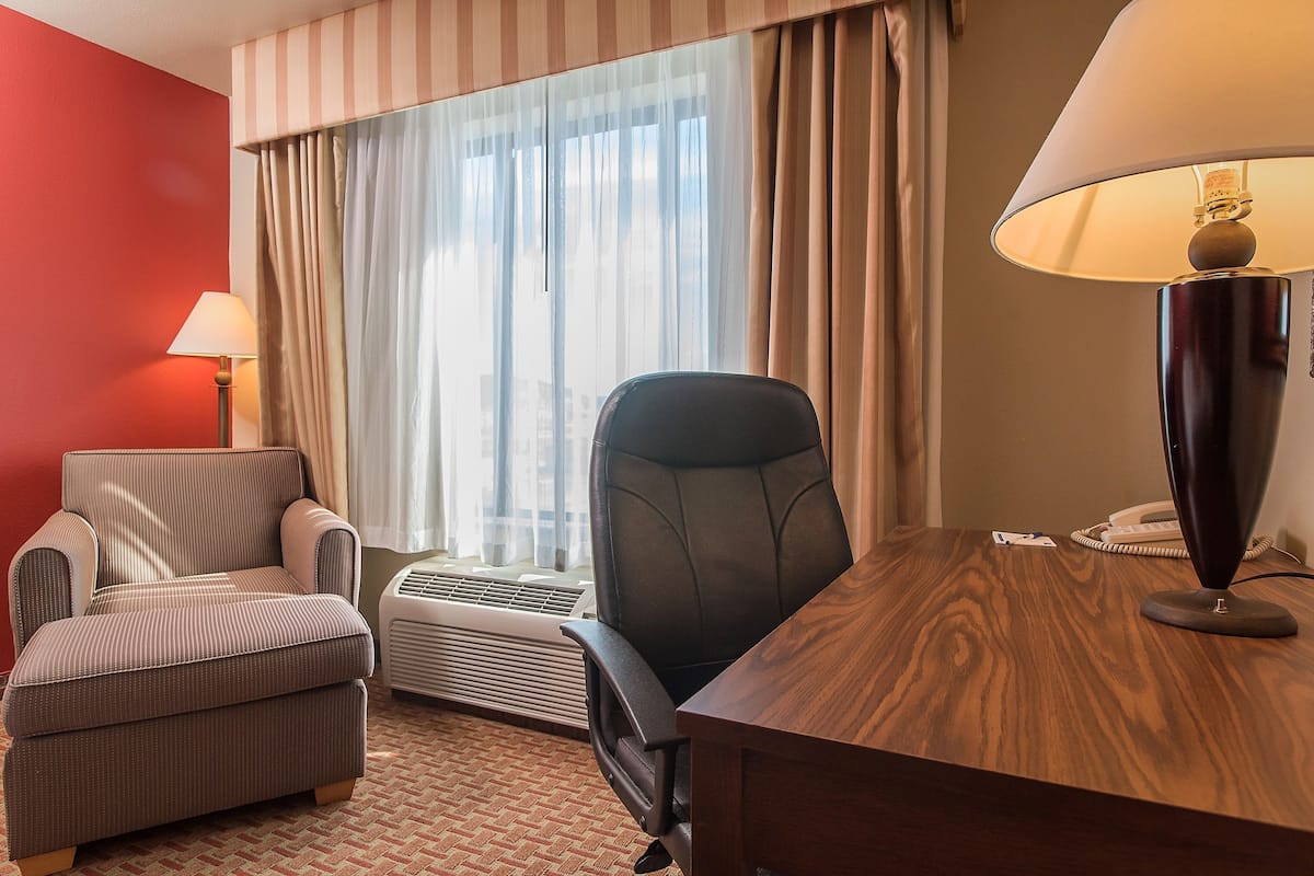 Escritorio, cortinas blackout y tabla de planchar con plancha