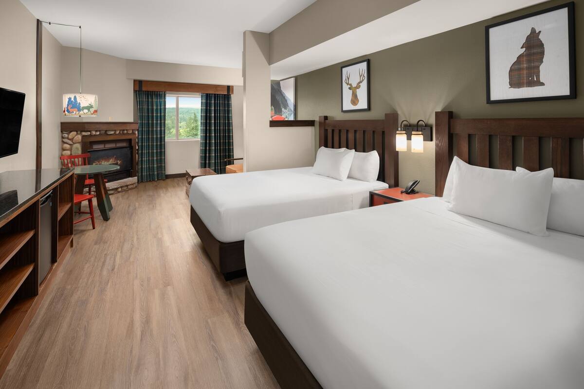 Habitación de hotel con dos camas, chimenea, televisor y zona de comedor.