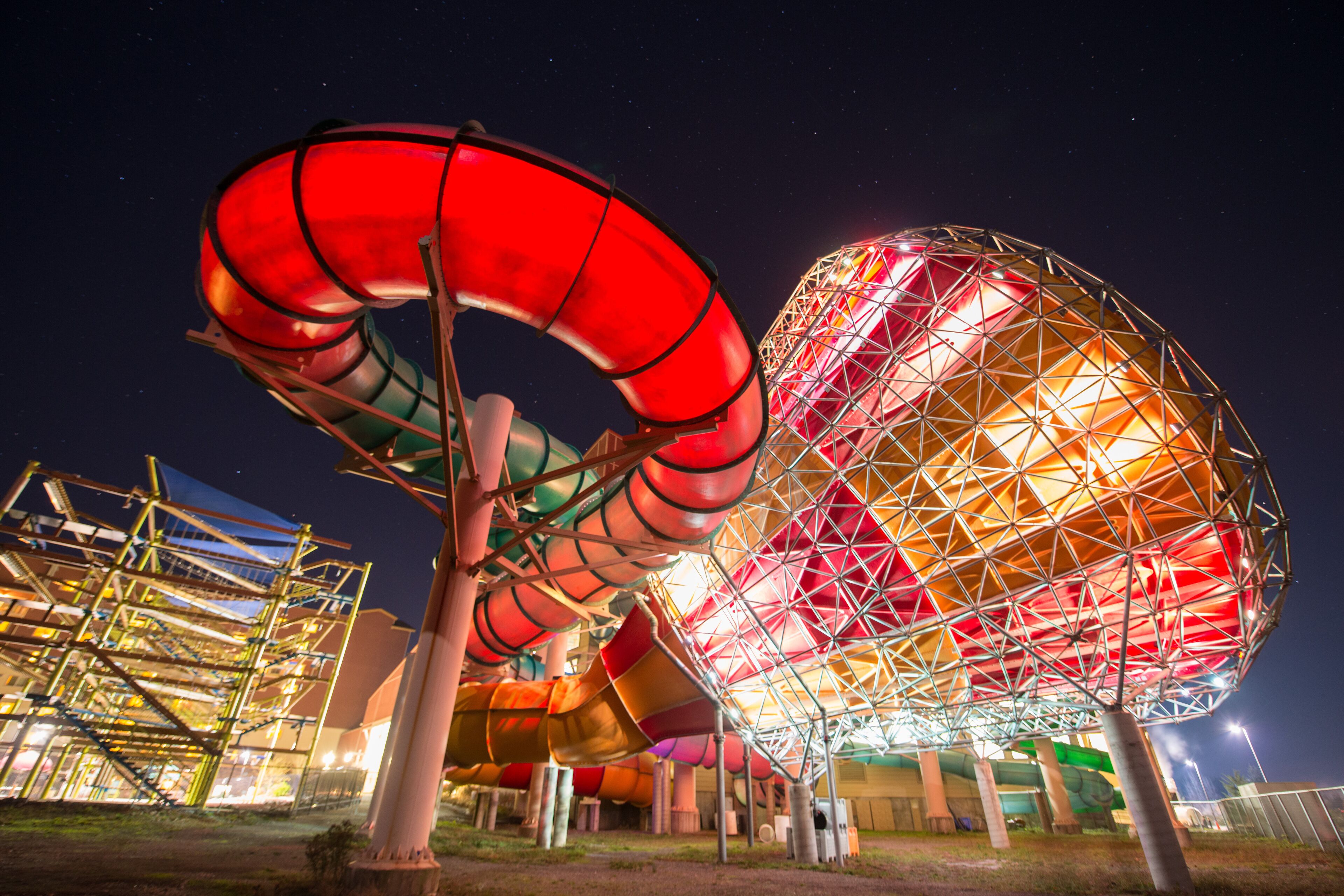 A large, spherical structure with a complex, geometric design, surrounded by various colorful slides and a metal framework.