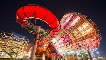 A large, spherical structure with a complex, geometric design, surrounded by various colorful slides and a metal framework.