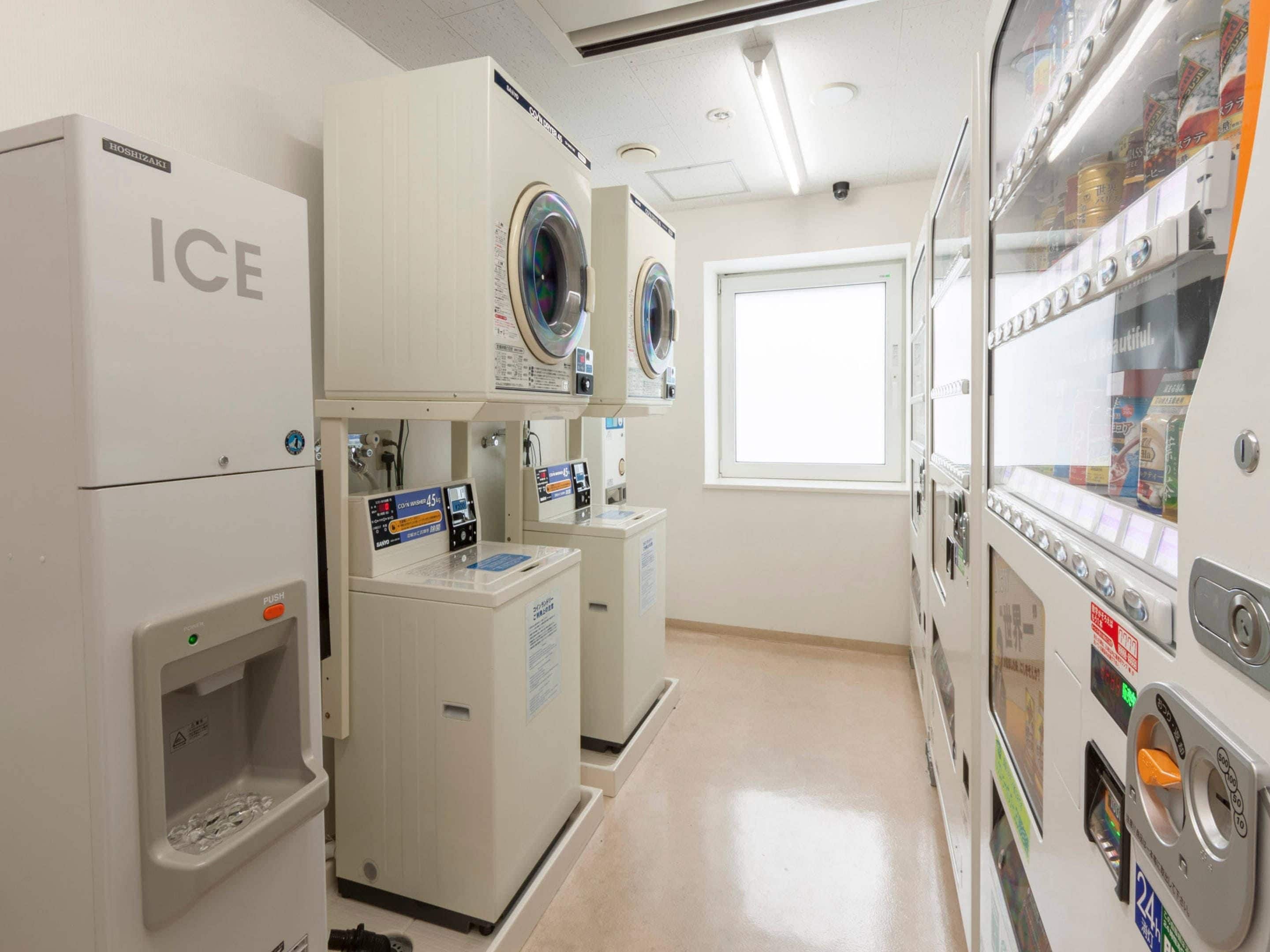 A laundry facility with washers and dryers, a vending machine, and a window providing natural light.