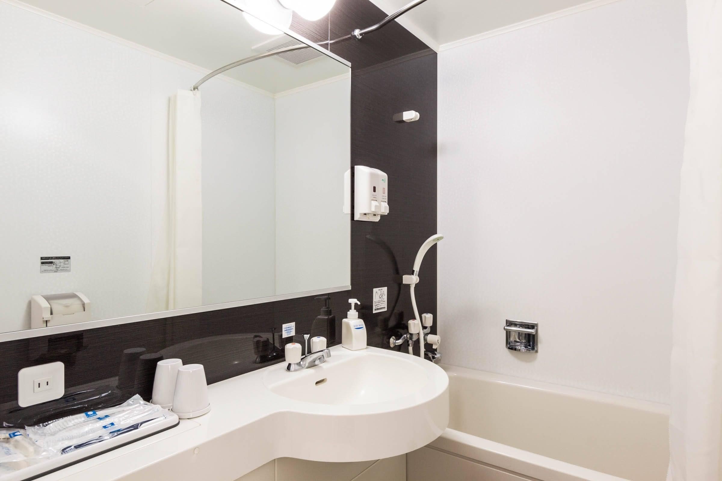 A modern bathroom with a white sink, a mirror, a shower, and a towel rack.