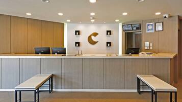 A reception desk with two computer monitors, a crescent-shaped wall decoration, and a security camera.