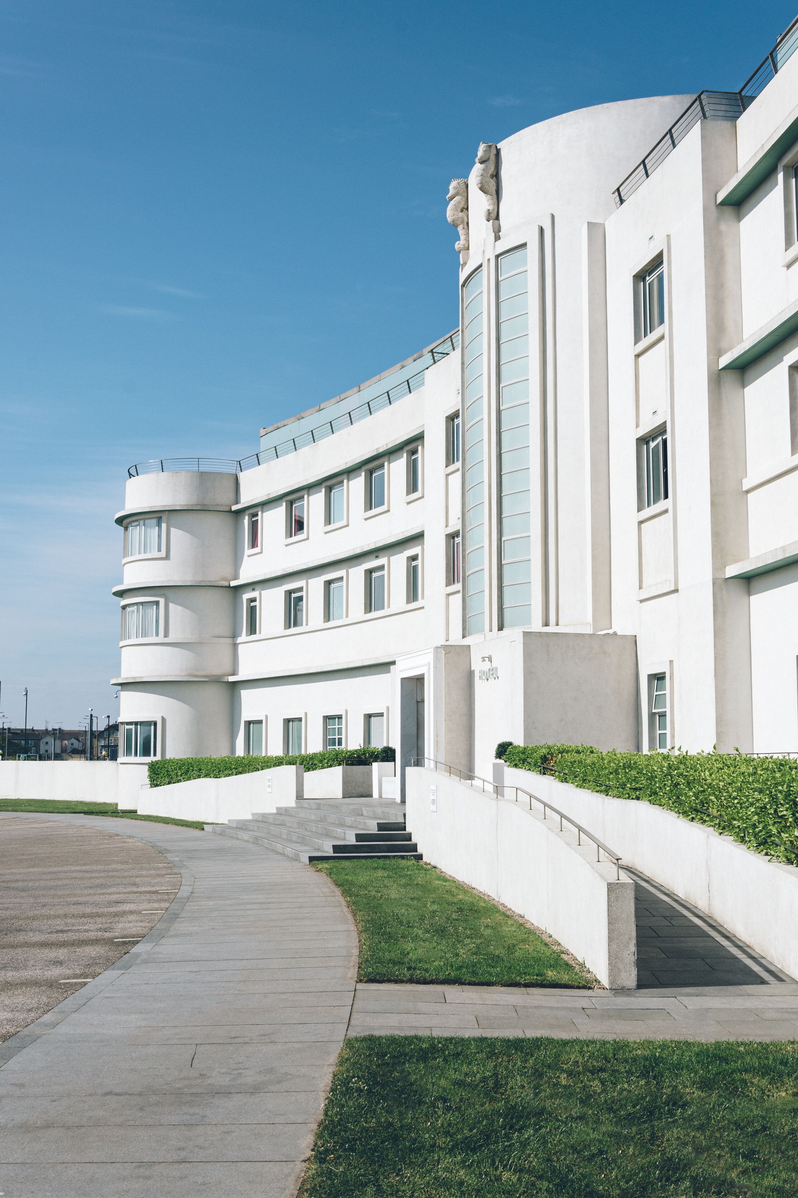 A modern building with a curved facade, multiple windows, and a staircase leading to the entrance.