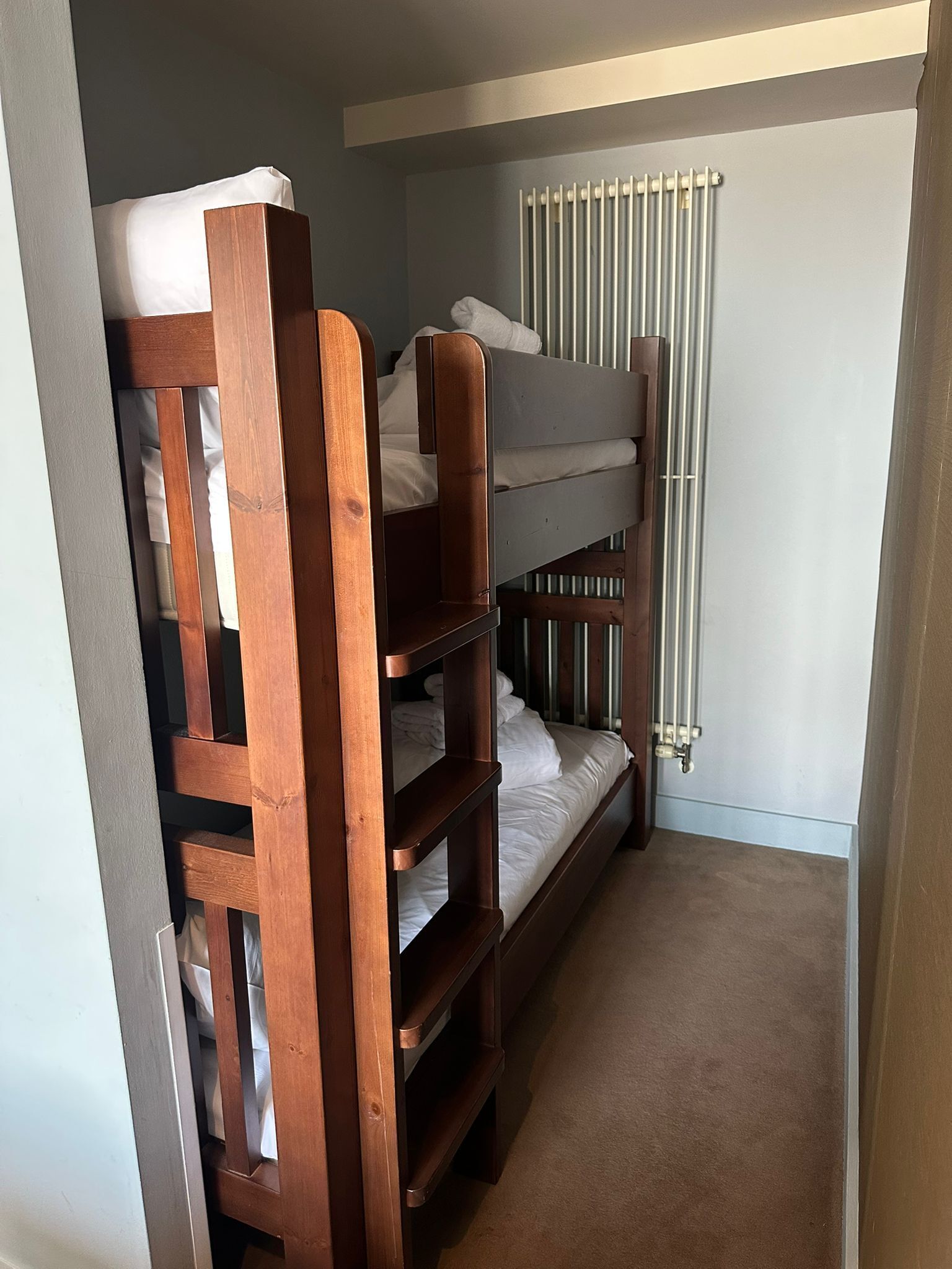A bunk bed room with a radiator and a door frame.